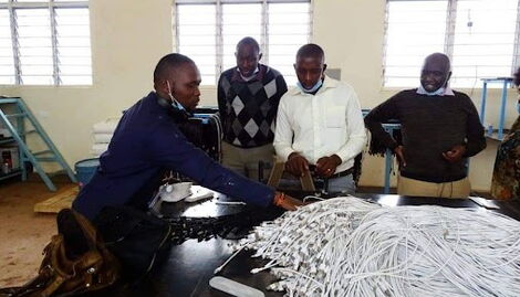 Antony Muthungu showcasing his locally manufactured USB cable at the factory in Kiangwaci, Kirinyaga County .