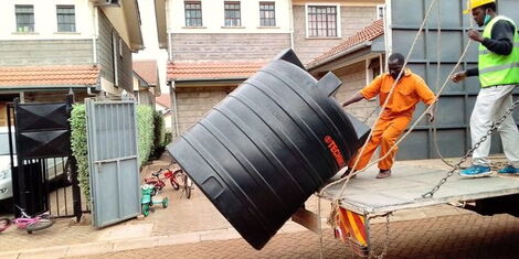 Two men ferrying a water tank for installation at an apartment in Nairobi County.