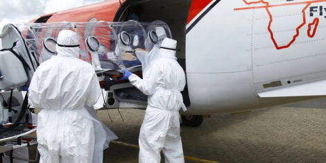 AMREF Flying Doctors personel load a portable isolation chamber onto a plane. 