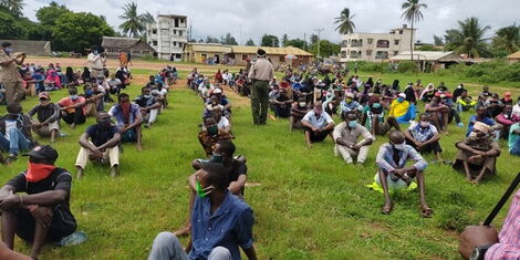 A police officer inspect youth awaiting to be listed under the Kazi Mtaani program phase 1.